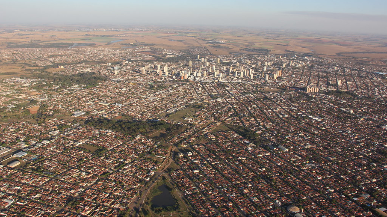 Vista aérea da cidade de Araçatuba, em São Paula, evidenciando a presença de casas e prédios, e o céu claro e limpo no horizonte.