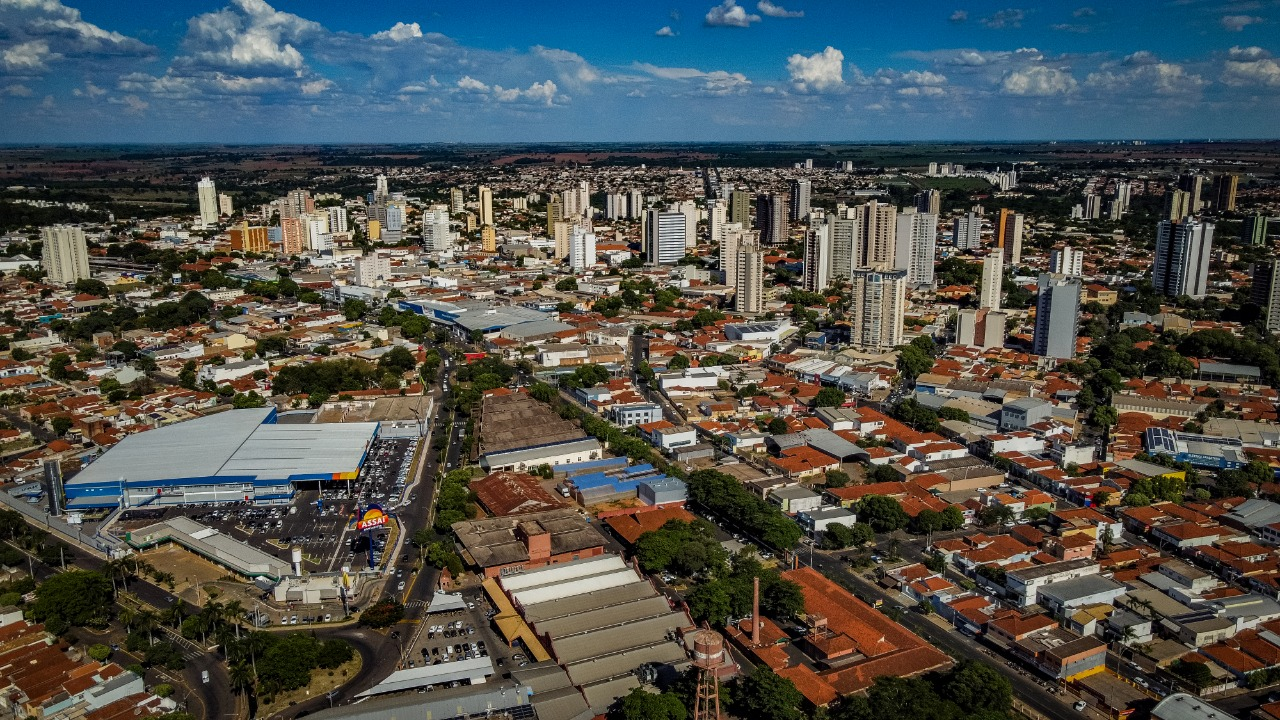 Araçatuba em dia de sol, com vista de cima que mostra casas, prédios e árvores, com céu claro e poucas nuvens.