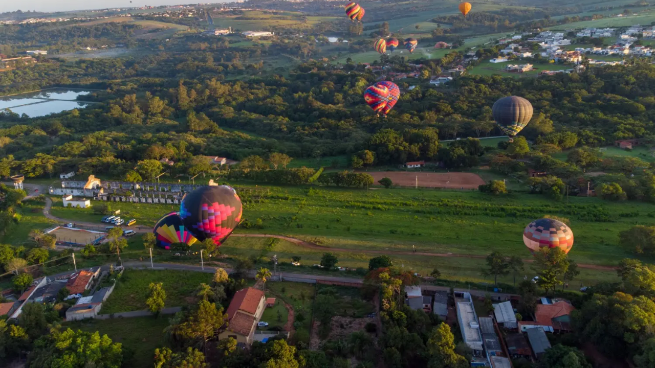 Na foto, vemos balões de ar coloridos voando alto sobre uma área verde de Boituva, no interior de São Paulo.