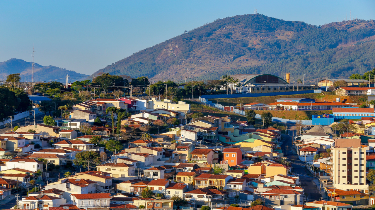 Foto de casas e construções de Bragança Paulista, com um morro ao fundo sob um céu claro e limpo.