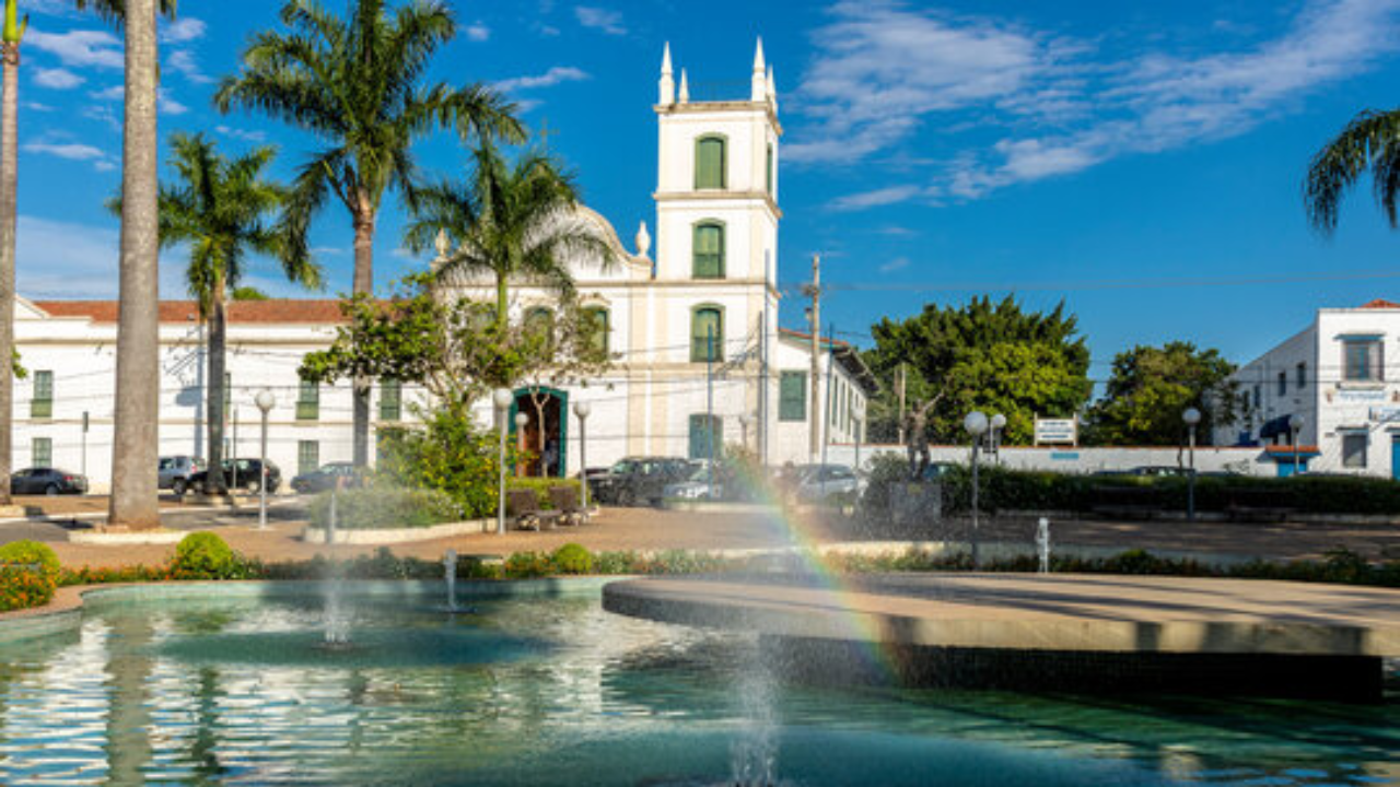 Edifício de Itu, com arquitetura típica do período colonial, com as paredes brancas, e palmeiras e uma pequena fonte de água na frente.