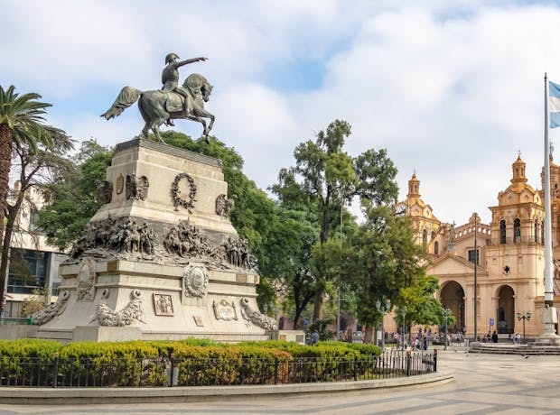 Praça central de Córdoba, Argentina, com estátua do General San Martín, Catedral de Córdoba ao fundo e bandeira argentina.