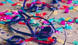 Confetes coloridos em azul, vermelho, rosa, roxo, azul e amarelo ao chão após uma celebração de carnaval.