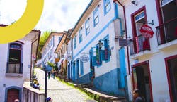 Imagem de uma das ruas da cidade de Belo Horizonte, em Minas Gerais. A foto mostra uma subida íngrime cercada por casas coloridas em dia ensolarado.