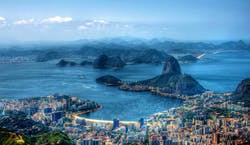 A imagem mostra uma visão panorâmica da cidade do Rio de Janeiro, com seu mar azul, montanhas em destaque e a orla da cidade.
