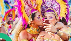 Duas mulheres com fantasias carnavalescas, sorriem enquanto tiram uma foto.