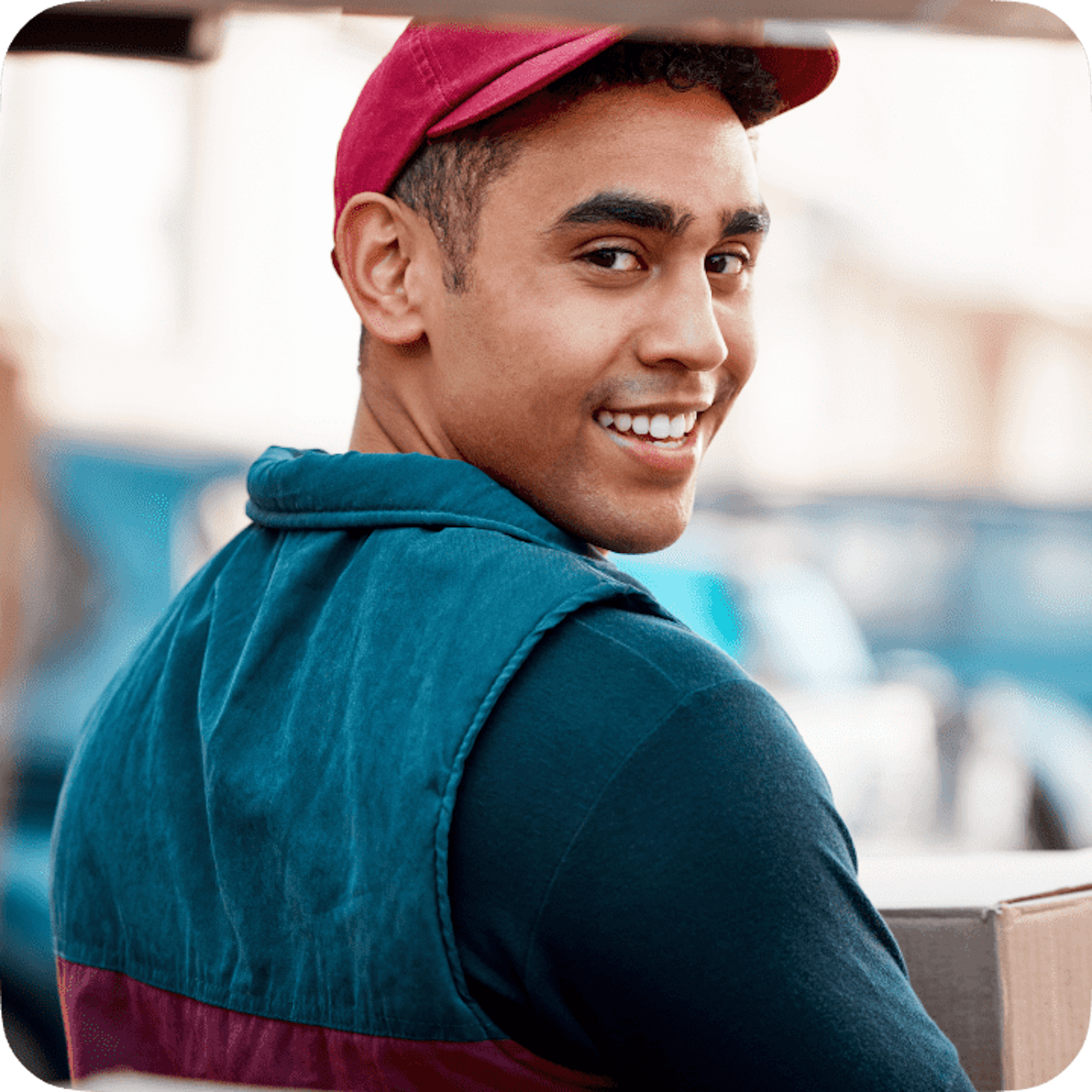 Happy delivery driver in casual attire with a cap, looking over his shoulder with a smile