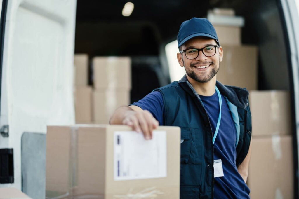 How to Make Money as a Courier: Courier driver smiling with boxes and vehicle in the background.