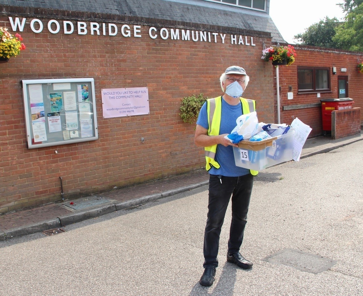 A volunteer stands outside of Woodbridge Community Hall.