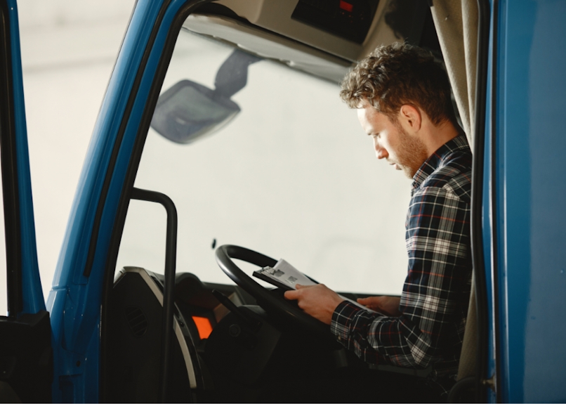 A man is sitting in his delivery truck about to make another delivery.