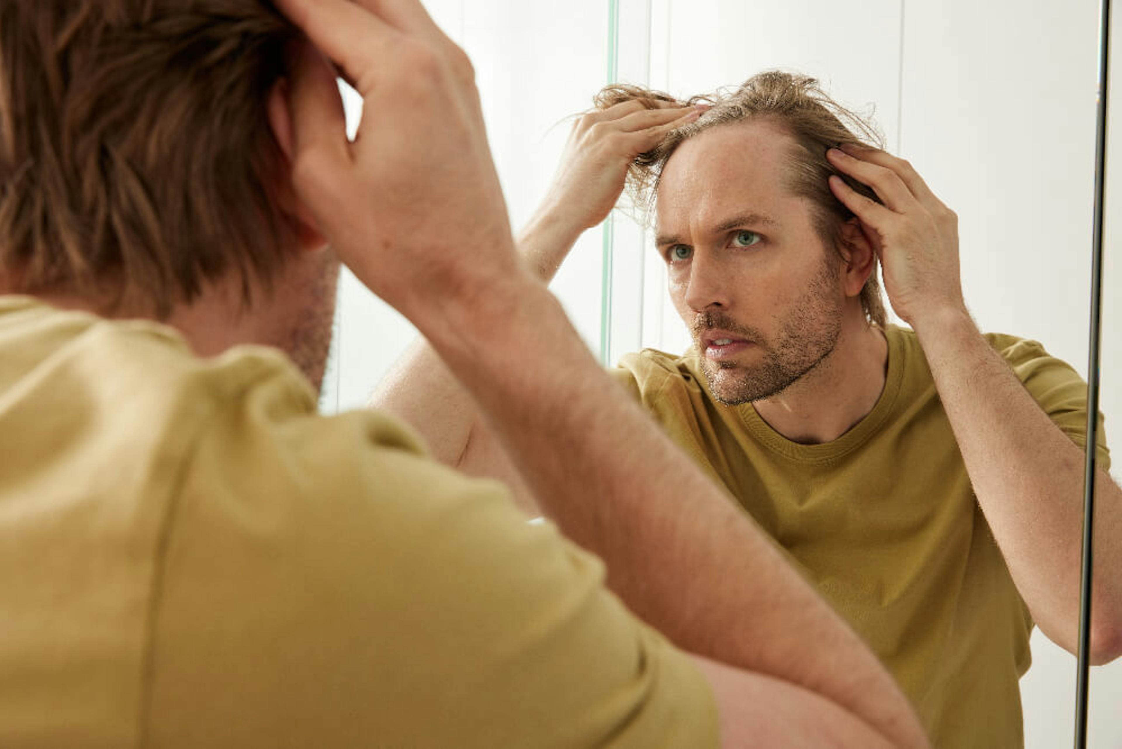 A man checking his hairline