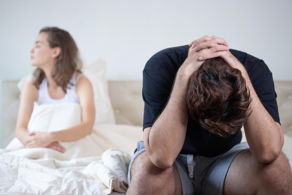 couple sitting in bed looking very sad