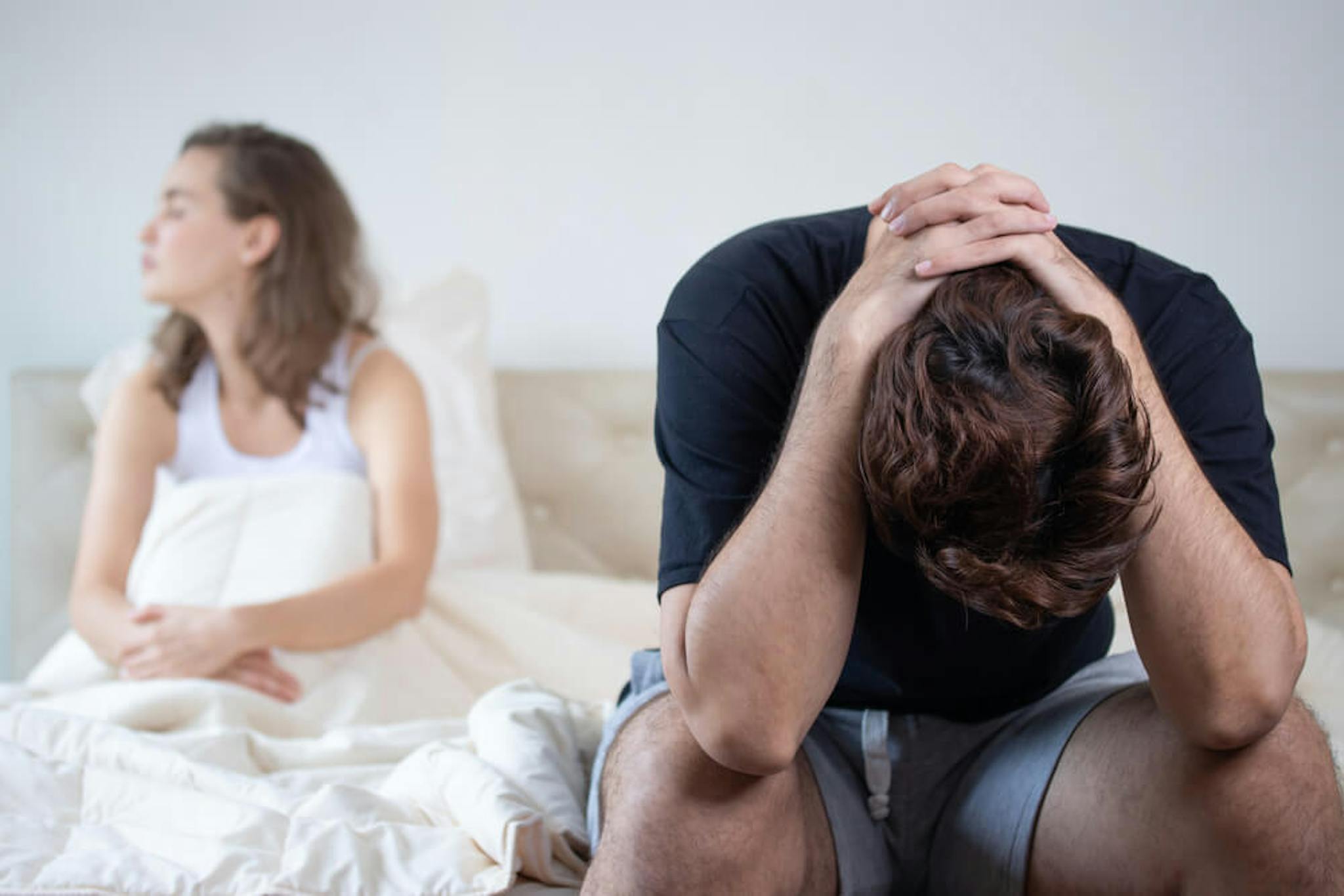couple sitting in bed looking very sad