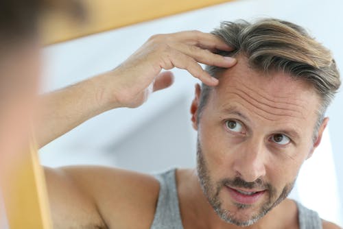 A man checking in the mirror his hairline