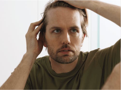 Man looking at his hair in the mirror