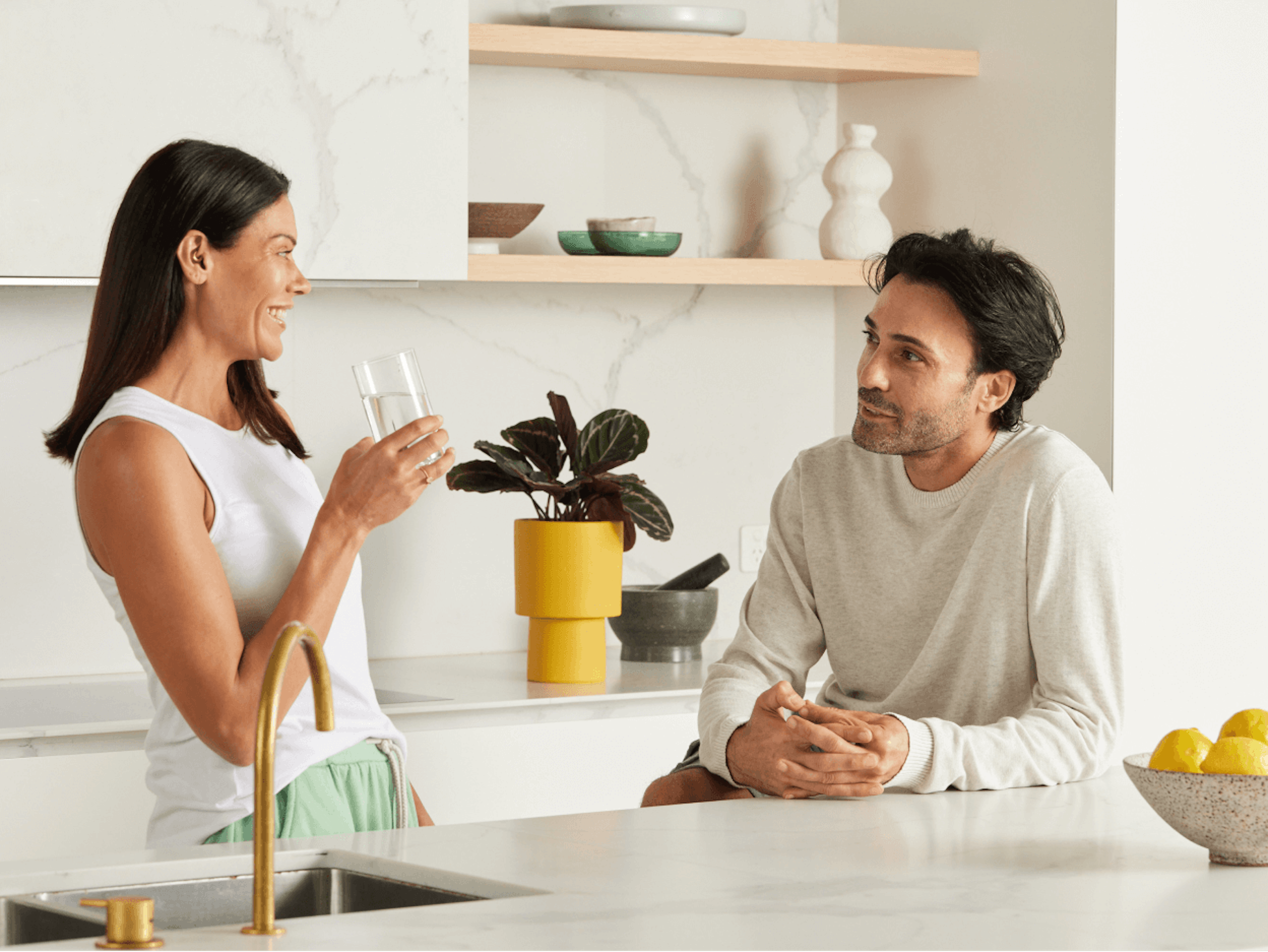 A man and woman having a friendly conversation in a kitchen.