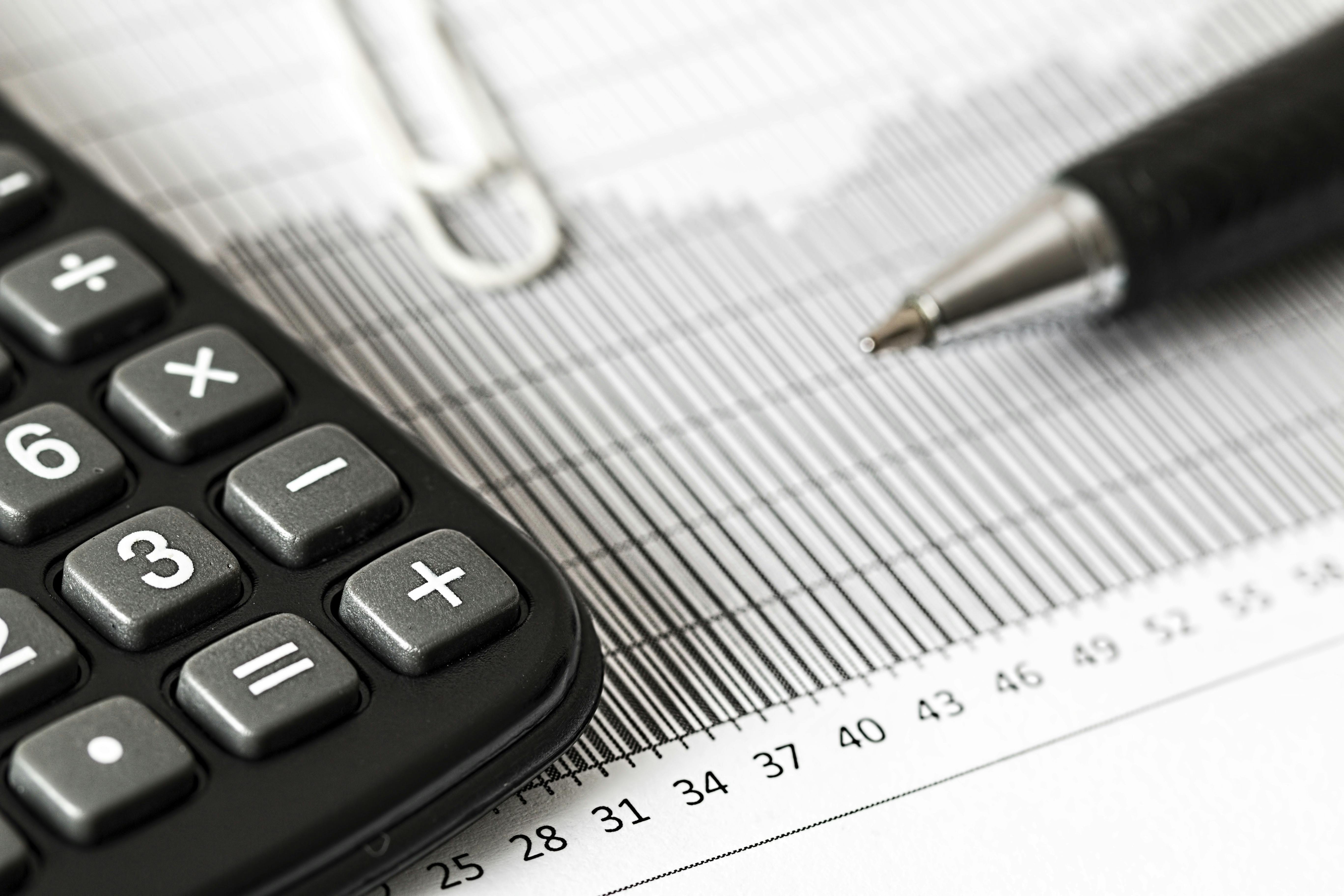 A calculator and ballpoint pen lying on top of a spreadsheet