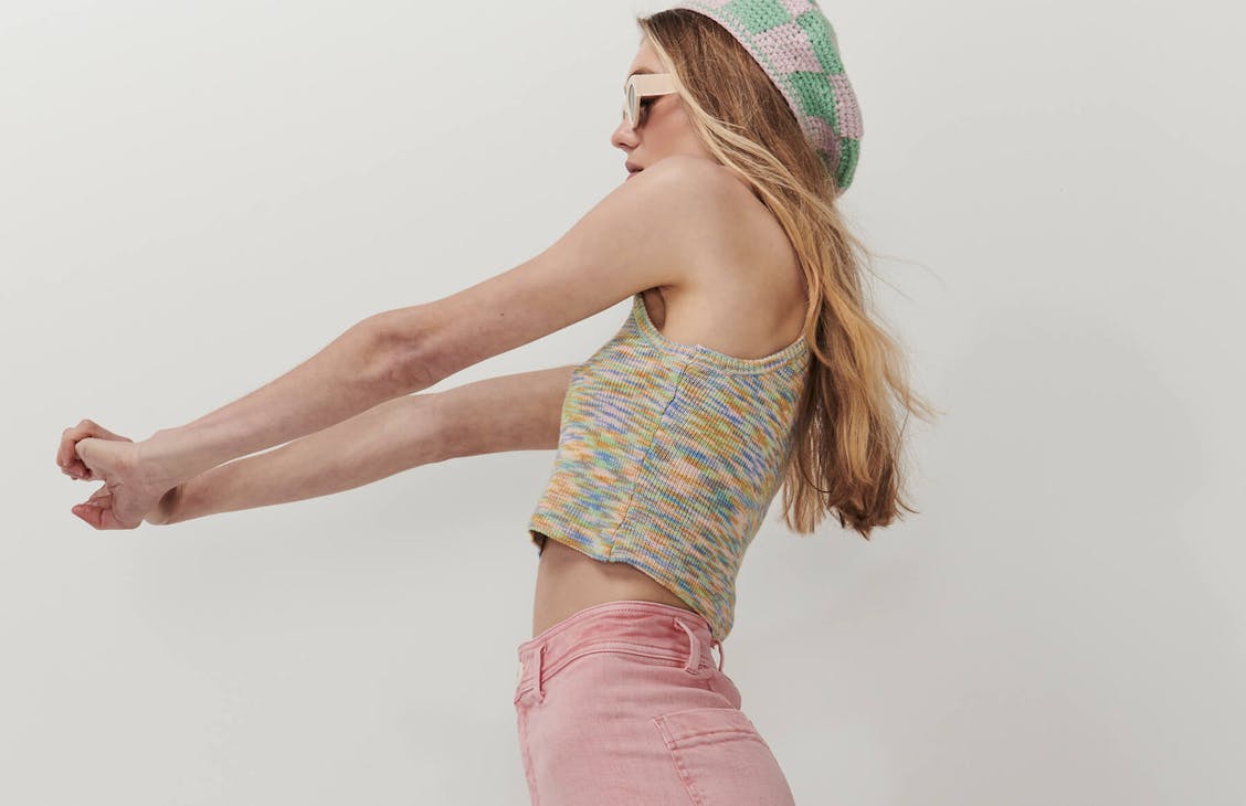 Female model wearing the Farout Cami in Fruity Space Dye, arms are out in front, standing side on.