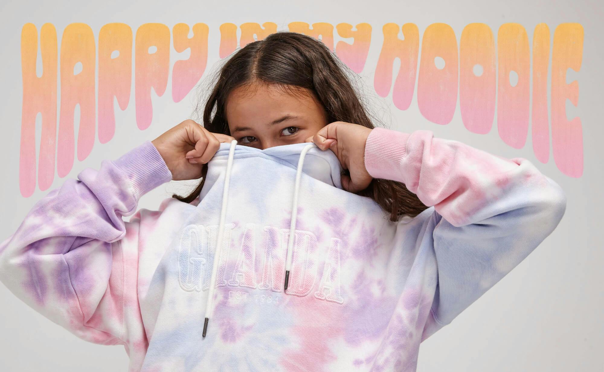 Teen banner with hand drawn bubble writing around the image of a teen girl wearing the Hailey hoodie. Text reads "happy in my hoodie"