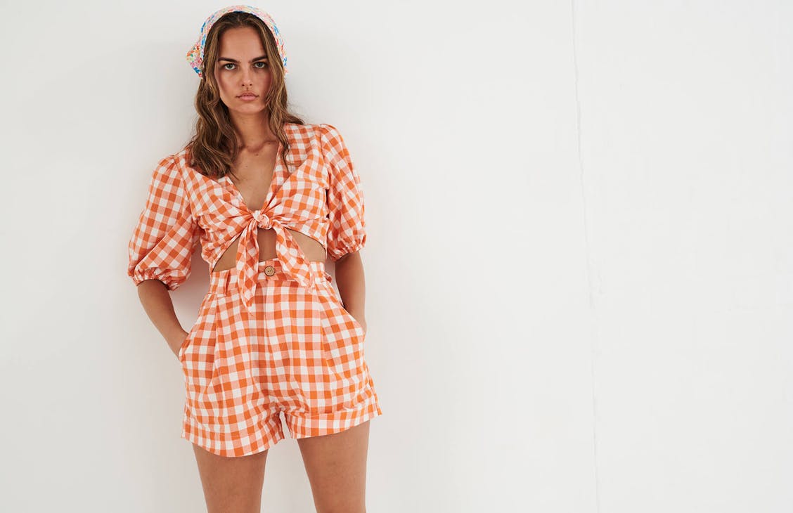 Female model wearing the Oxford Shorts in melon check.