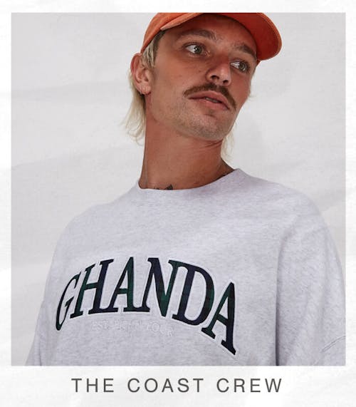 Image of male model in studio wearing the Coast Crew and the classic cap in washed orange. White border around it with text at the bottom "The Coast Crew"