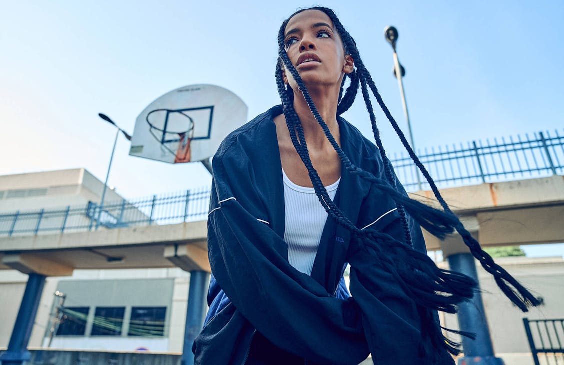 Image of female wearing match sports jacket and trackies she is at a basket ball cour
