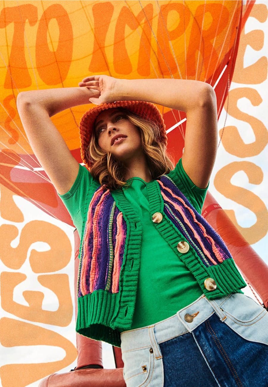 Image of model wearing the Wave Jeans, Quinn Tee and Kylie Vest with hot air balloon behind her. Text warps around the model reading 'Vest to impress'