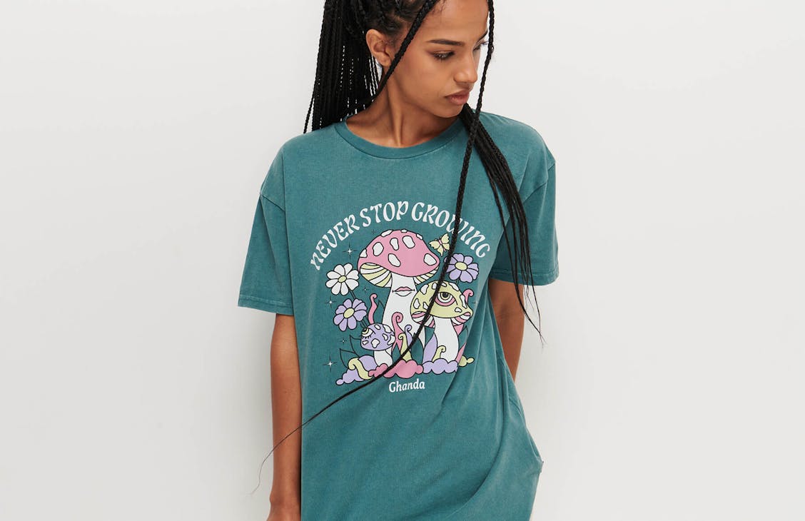 Female model wearing the band tee in ocean teal with never stop growing print 