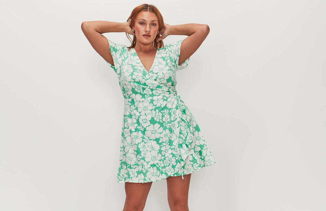 Image of female model wearing a green and white floral wrap dress. 