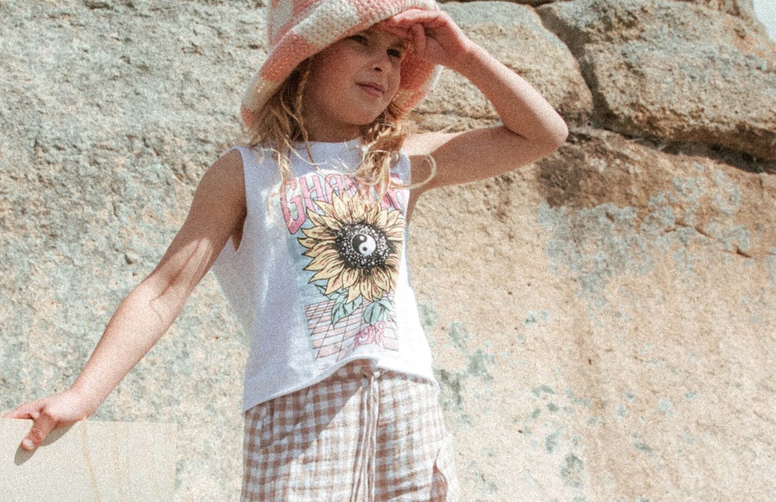 Female model wearing the Trippy Sunflower Crop singlet and Gwen hat.
