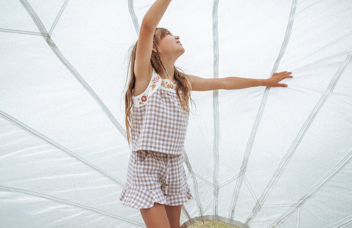 You model plays underneath a parachute wearing the Frenchy Top and Dreamer Shorts in Sandy Check