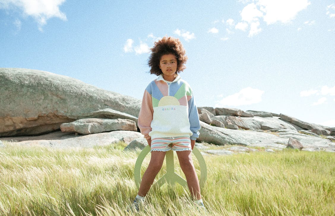 Young female model wearing the Charlie shorts in Eva stripe with the panel quarter zip in pastel sunrise.