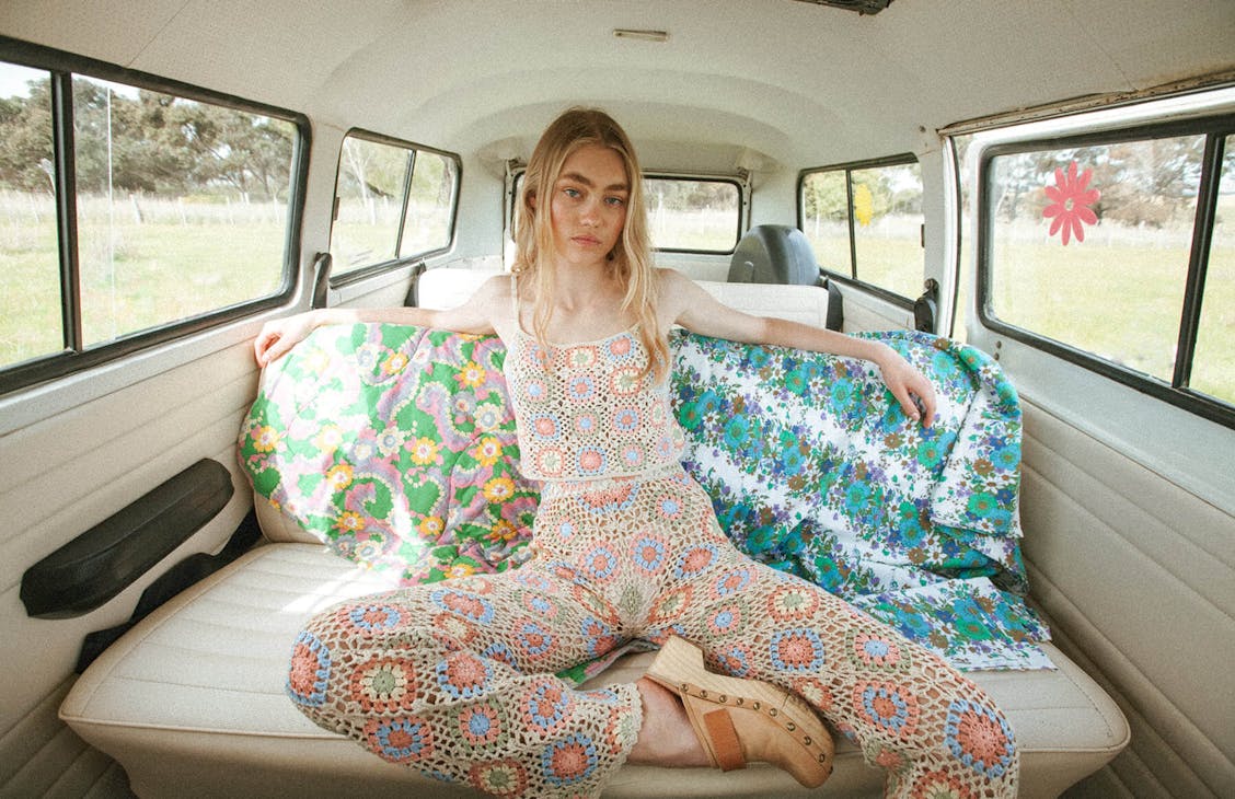 Female model wearing the Bambi crochet top and pants, sitting in the back of an old hippy van.