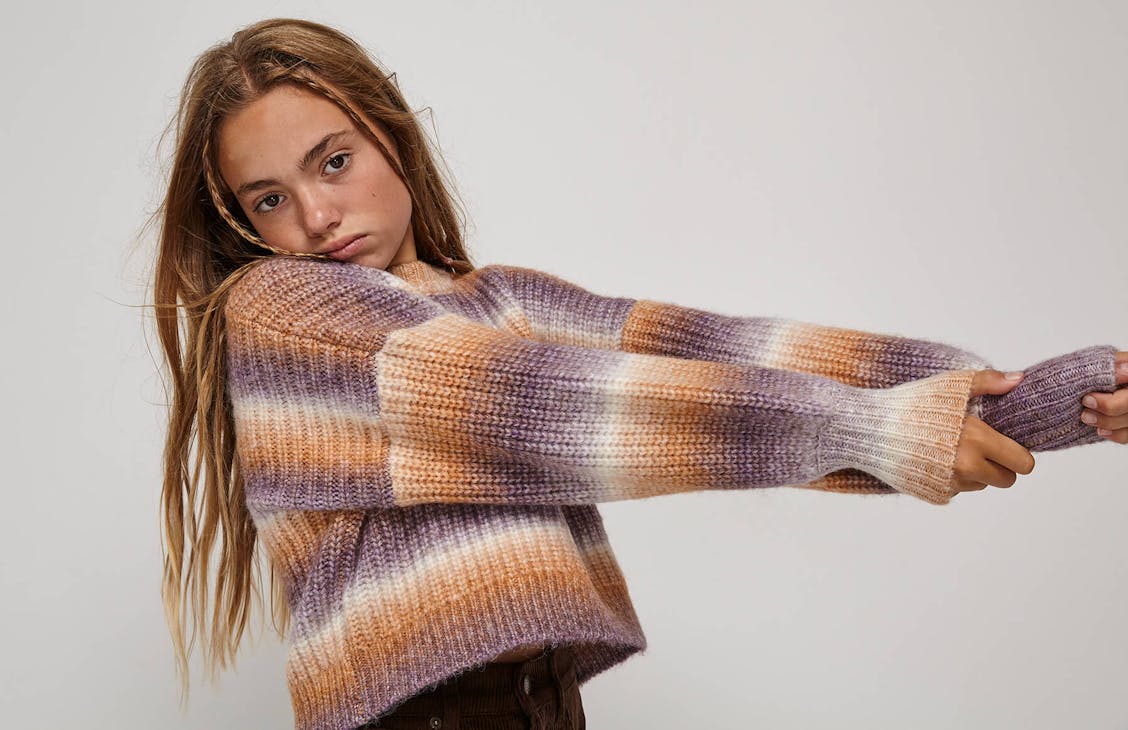 Young female model wearing the Rosie knit in mirage stripe.
