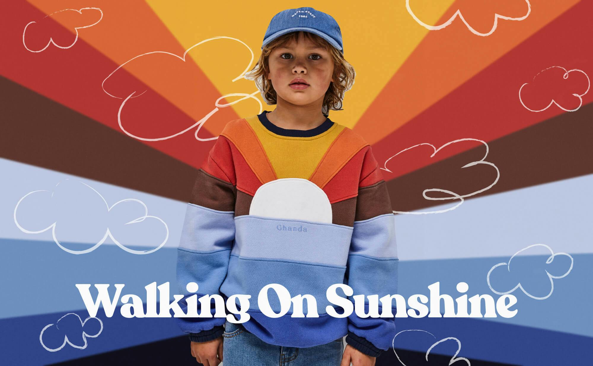 Colourful kids banner. Image of young boy wearing the sunshine crew, and the colours of the jumper extend onto the background. Drawn clouds surround him and the text "Walking on Sunshine" is white and centre in the lower bottom. 