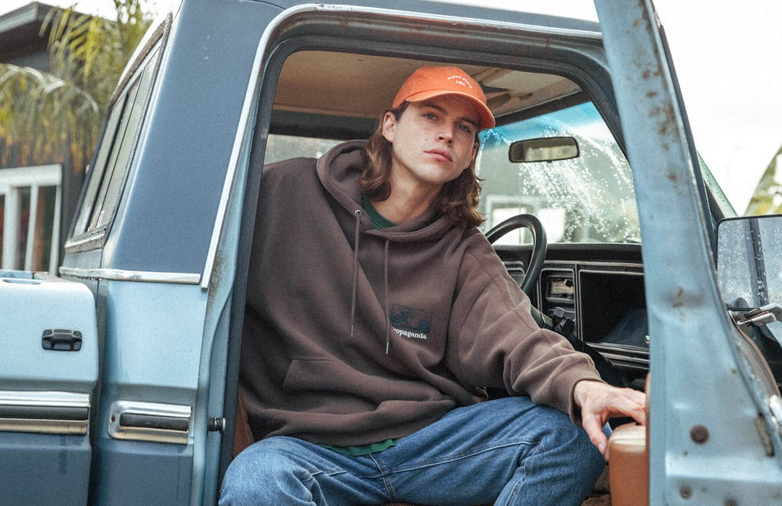 Image of male sitting in vintage bluer F1 truck. He is wearing the Rocky Hoodie in Acorn, Dogtown Jeans in blue denim and Classic Cap in Washed Orange