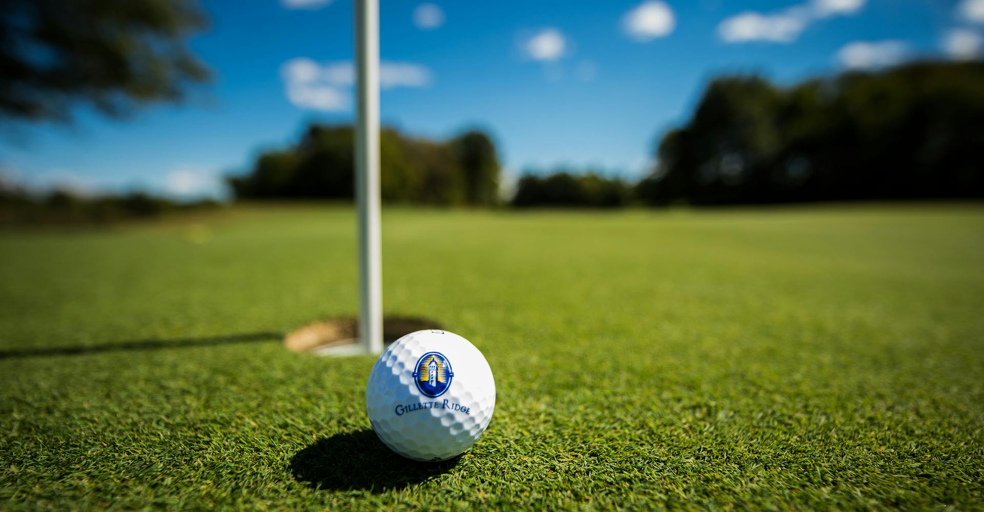 Gillette Ridge logo golf ball sitting on green near flagstick.