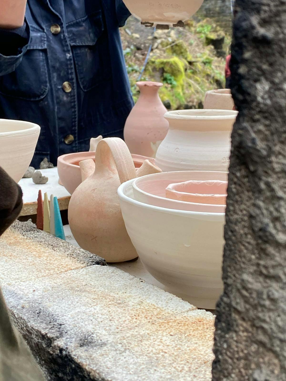 An image of bisqued ceramic pots in process of loading into a wood fired kiln.