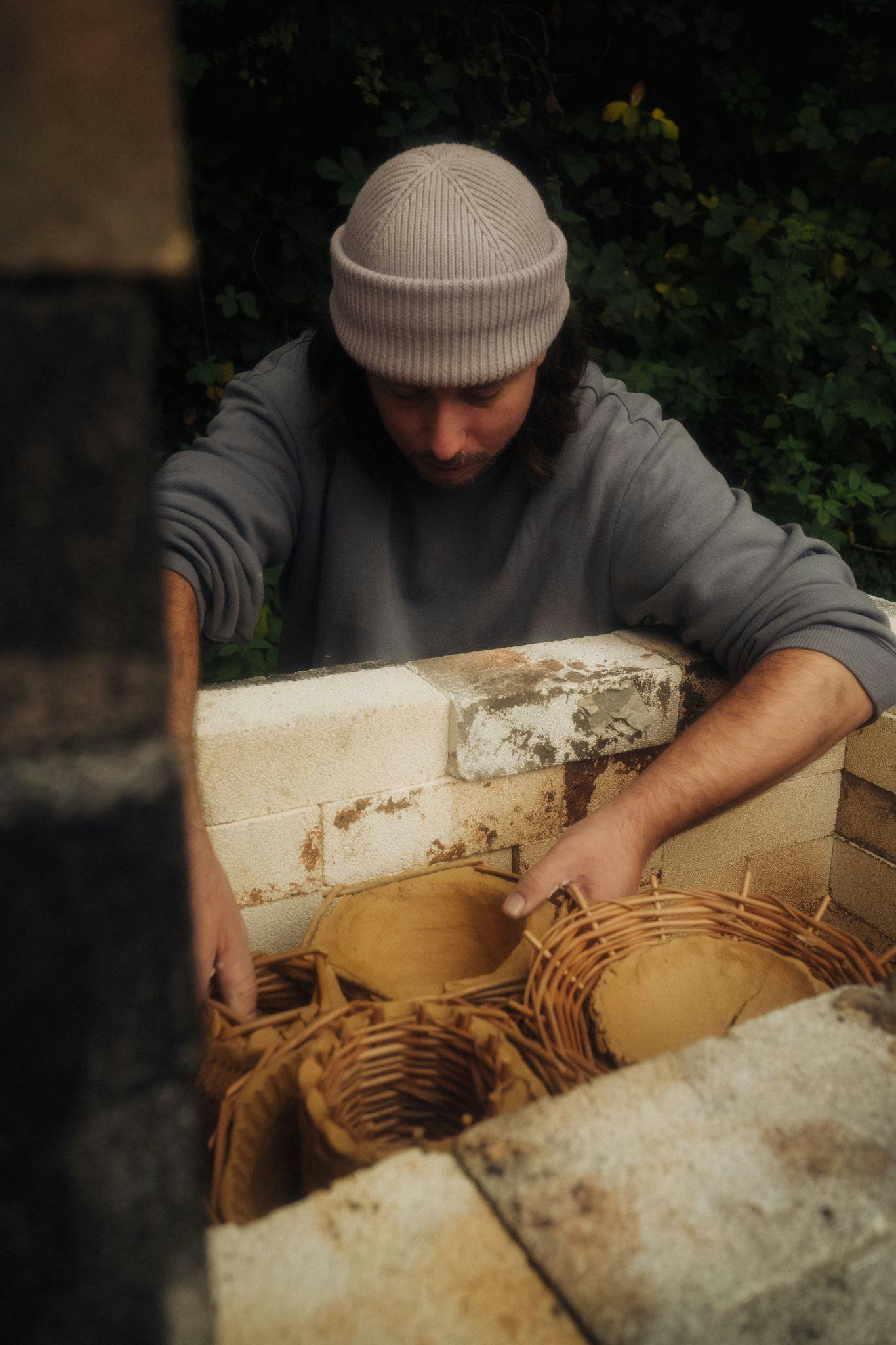 Phil Root is loading ceramic pots into a wood fired ceramic kiln.