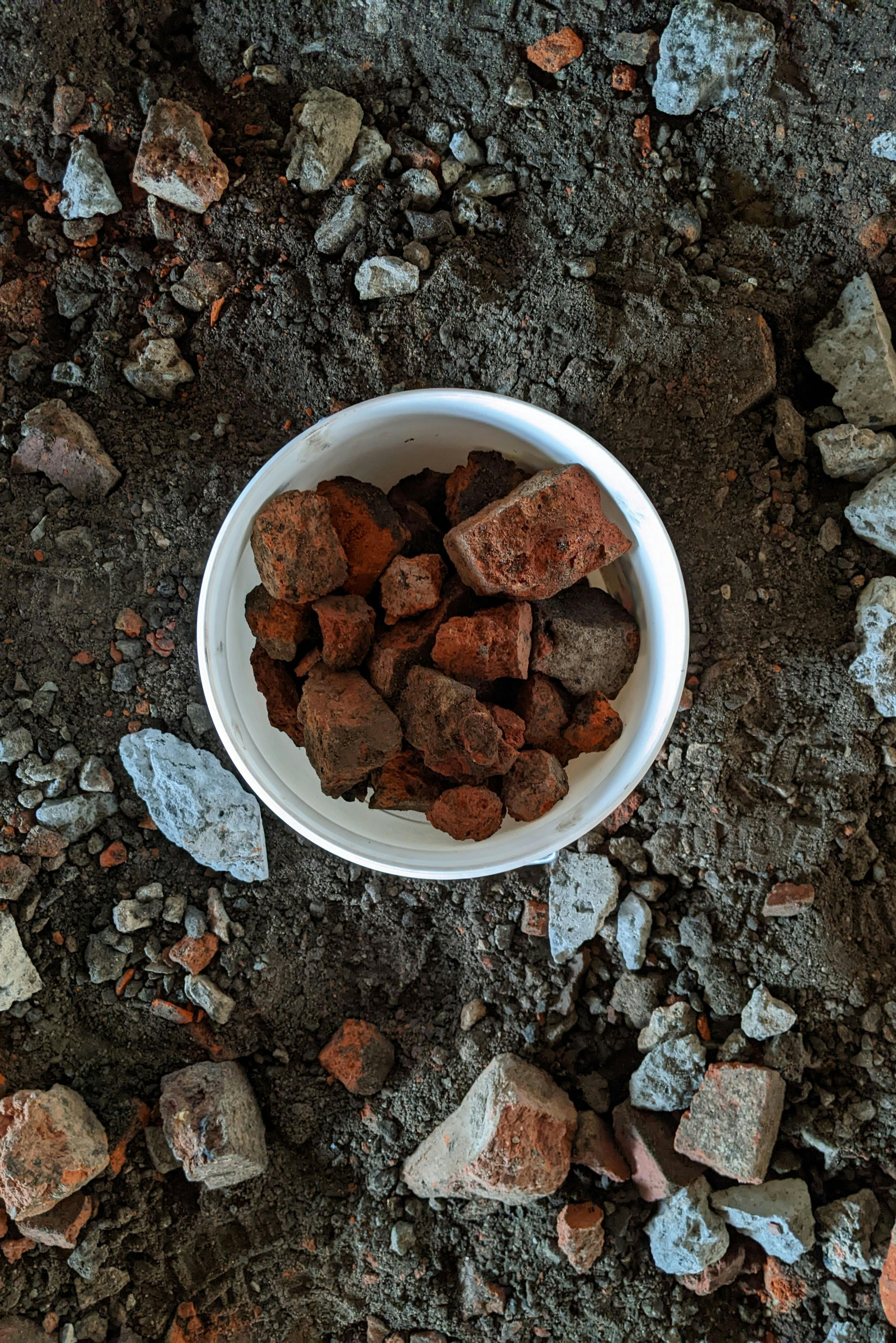 A bucket of red brick and stones. Waste material to be recycled and used as an ingredient in ceramic glaze making. 