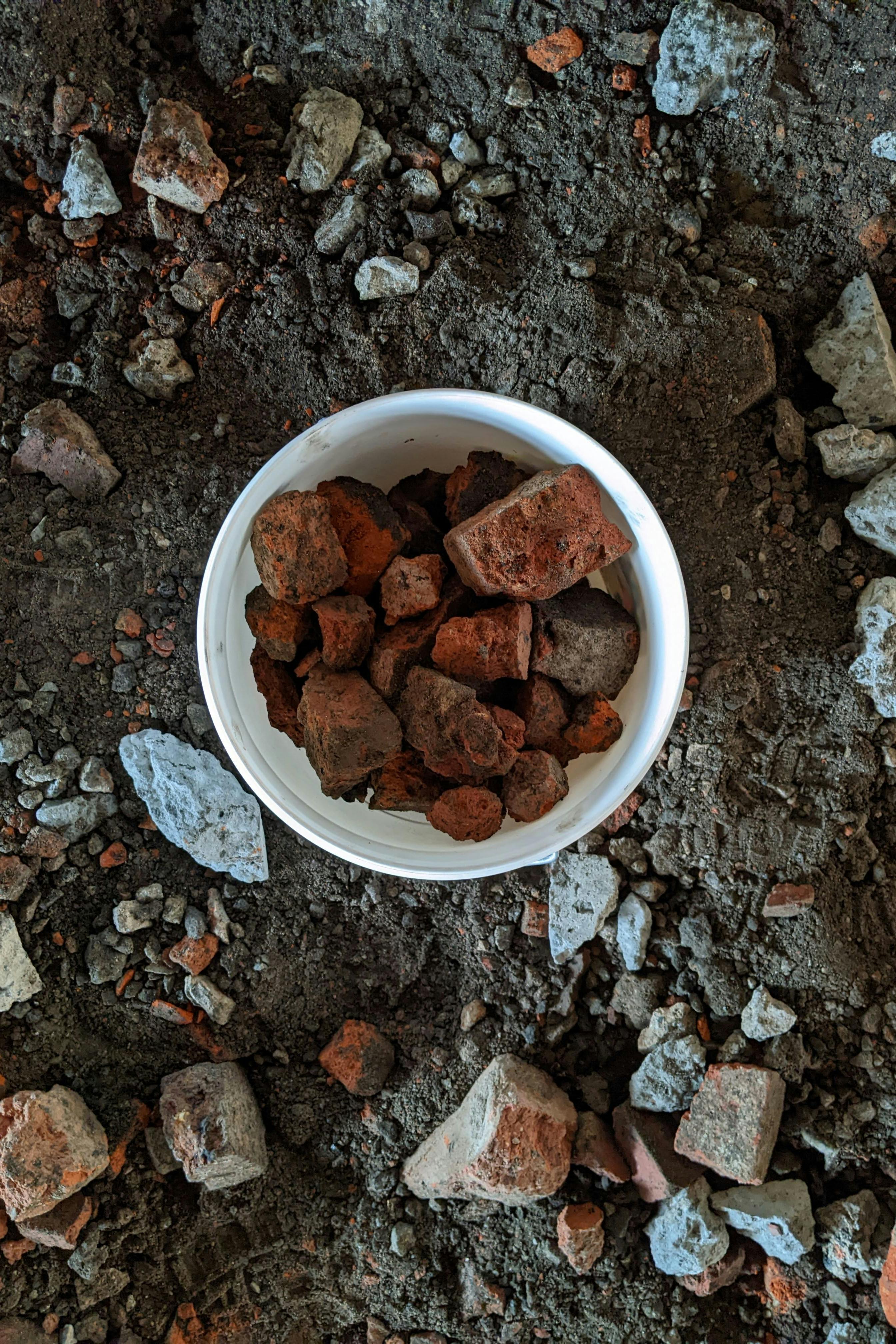 A bucket of red brick and stones. Waste material to be recycled and used as an ingredient in ceramic glaze making.