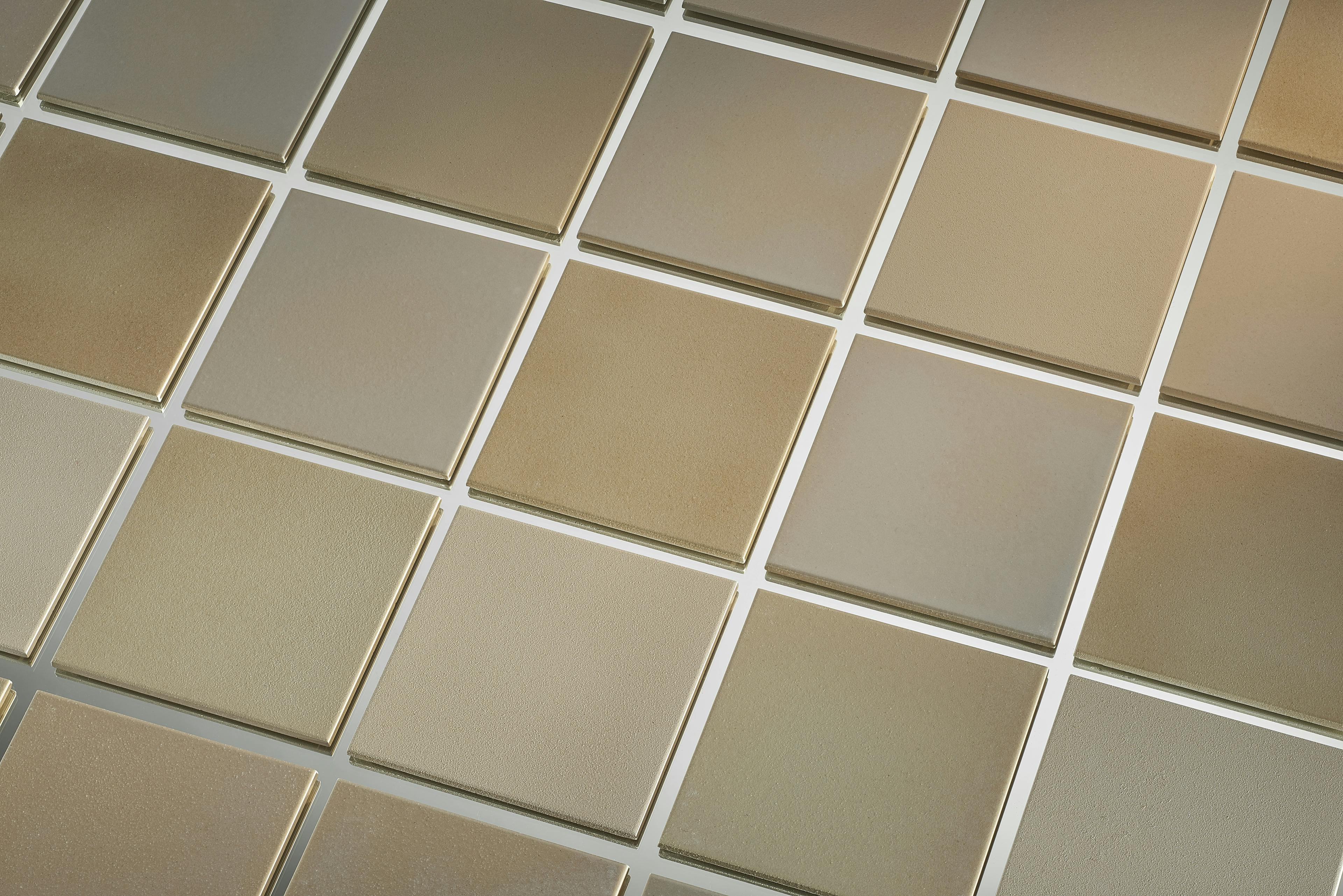 An image showing square ceramic tiles of different shades of grey and ochre. 