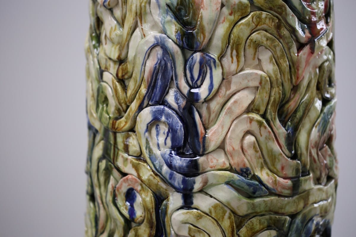 An image showing a zoom in of a glazes ceamic sculpture by Elena Gileva. It shows a green blue streaky an dshiny ceramic glaze surface.