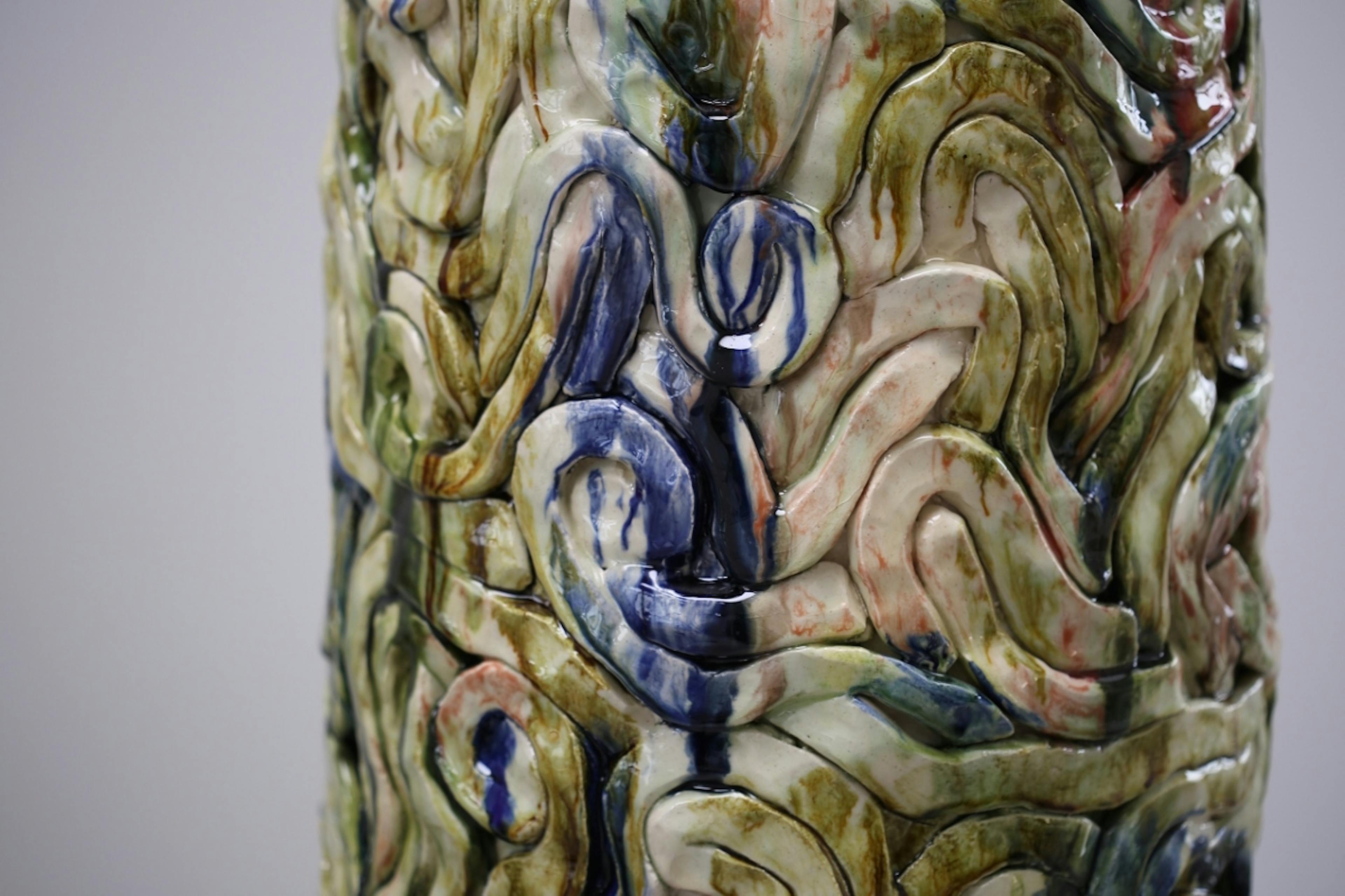 An image showing a zoom in of a glazes ceamic sculpture by Elena Gileva. It shows a green blue streaky an dshiny ceramic glaze surface. 