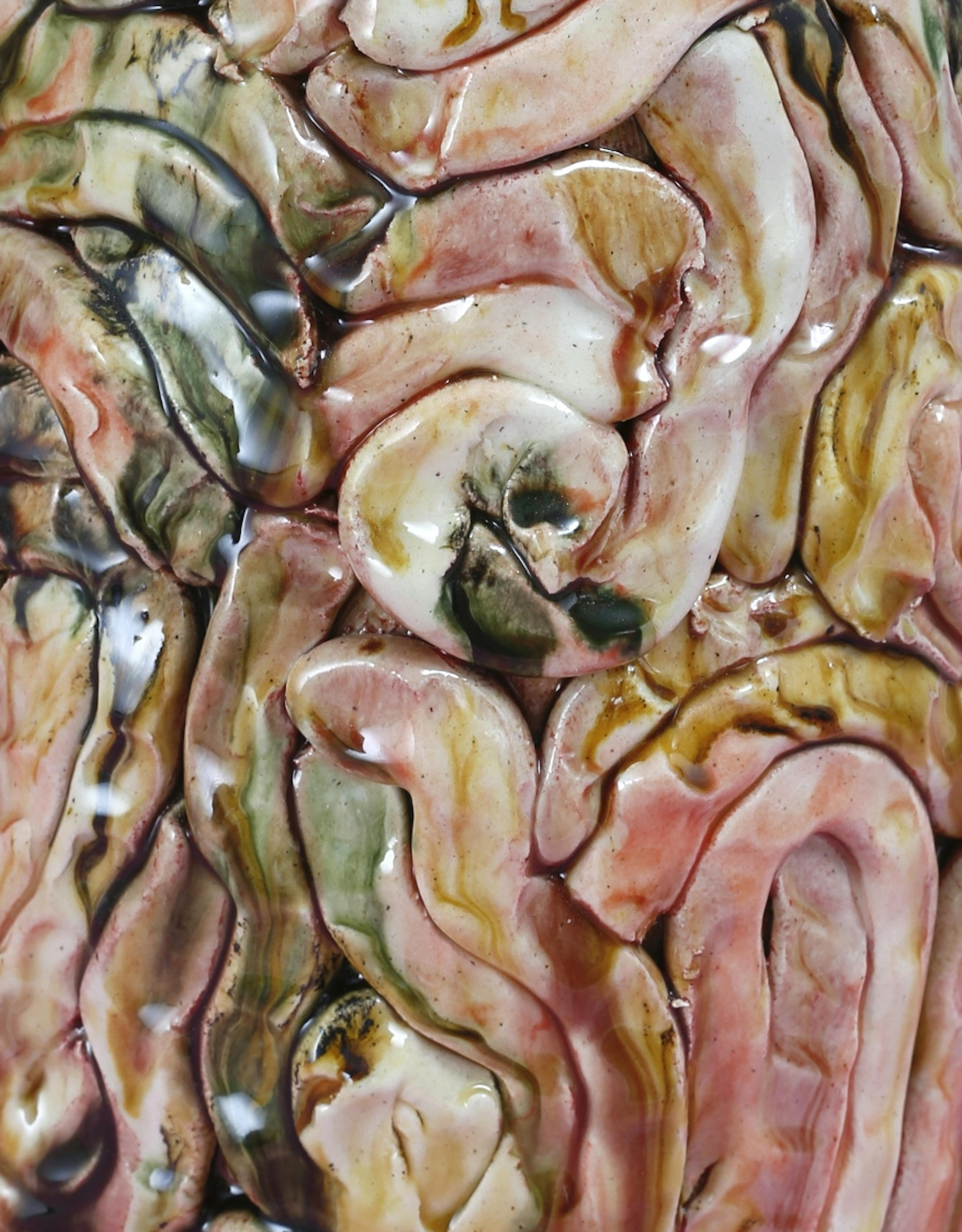 An image showing a zoom in of a glazes ceamic sculpture by Elena Gileva. It shows warm pink and ochre tones with streaks of green and blue. 