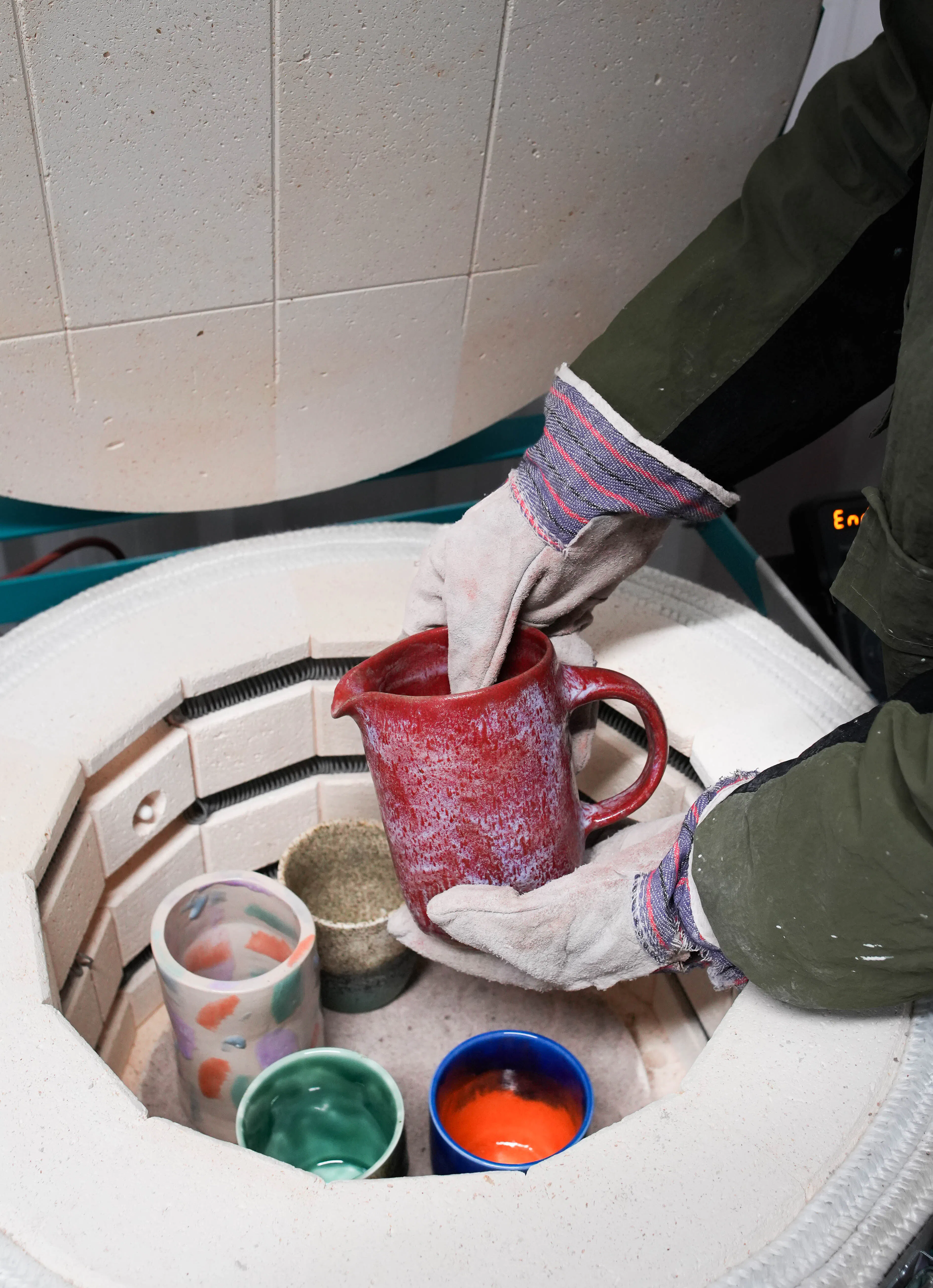 Loading a cermaic jug into pottery kiln
