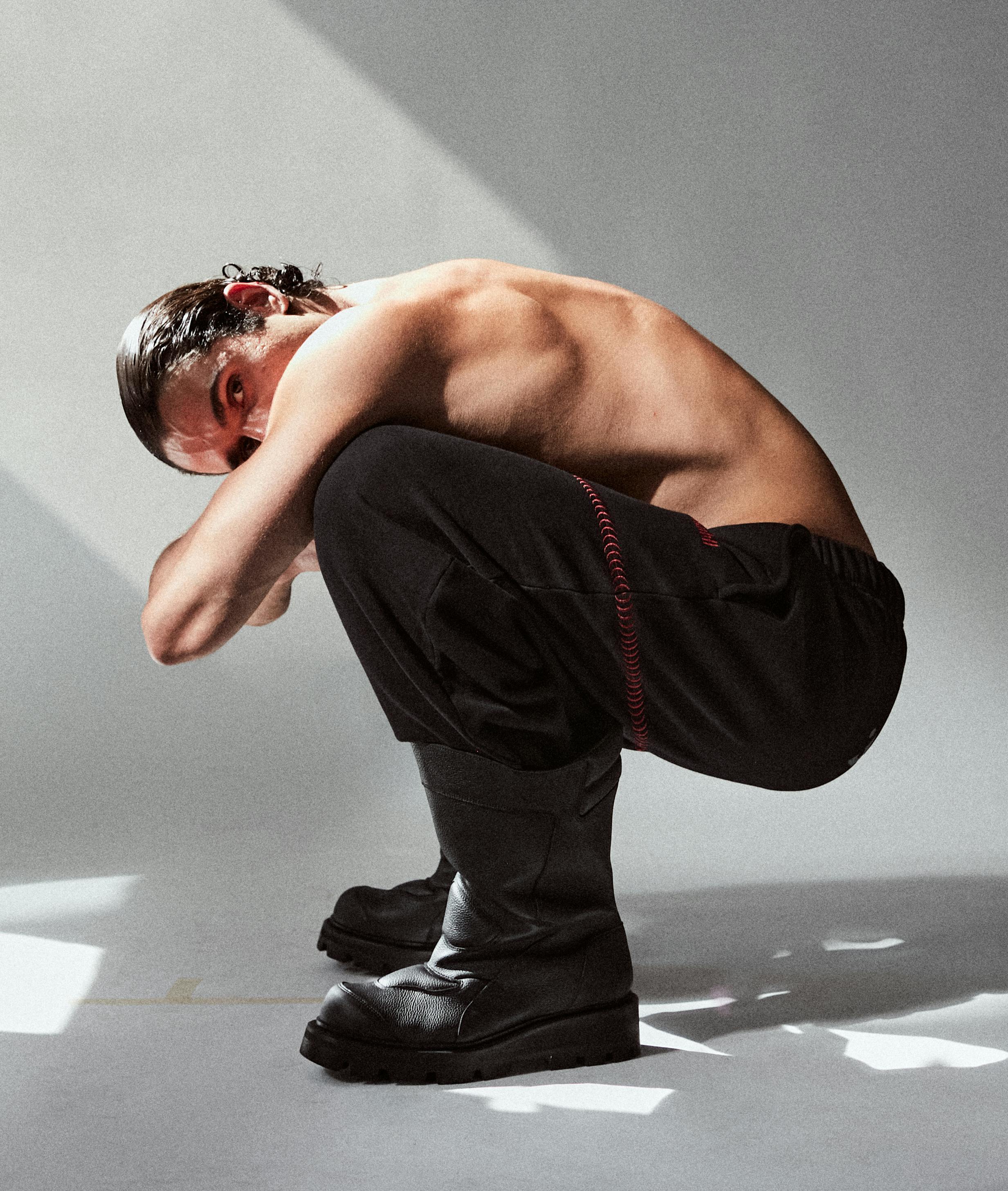 a man is crouching down on the floor with a bare chest