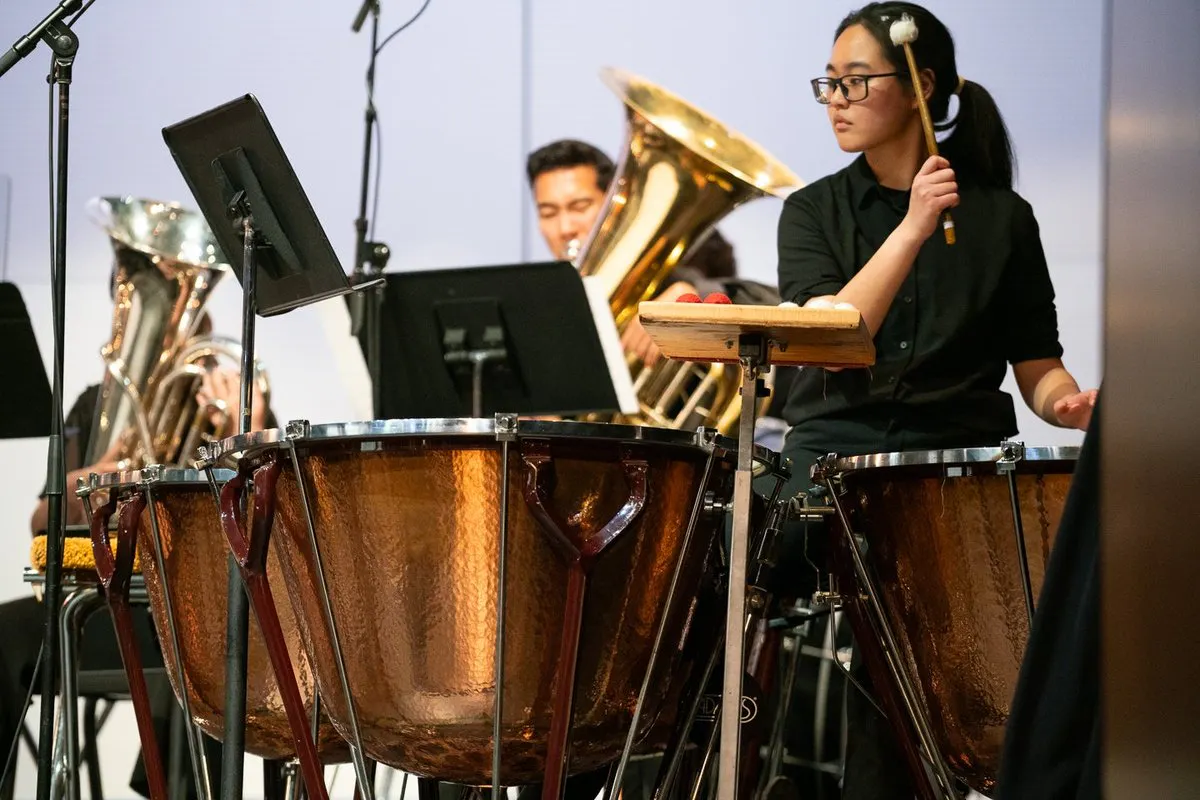 Close up of a timpani player on stage with an orchestra