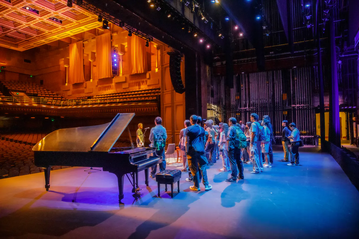 Students stand on the Royce Hall stage looking out into the auditorium during a behind the scenes tour