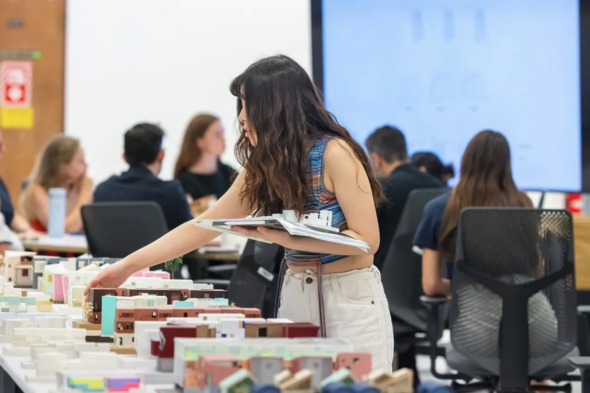 People move through an arts space, looking at physical items and a video